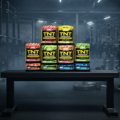Stack of TNT Nuclear supplement containers in various flavors on a dark background
