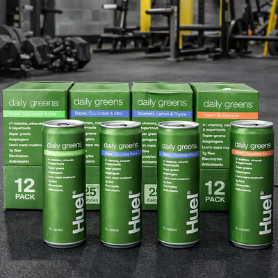 Huel Daily Greens Cans on a gym floor.