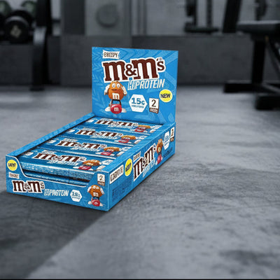 Box of M&M's High Protein candy bars on a gym background