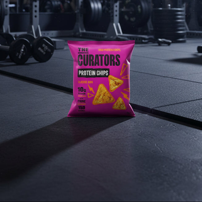 Pink packaging of 'The Curators' protein chips bag on a gym floor