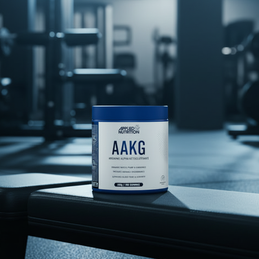 Container of Applied Nutrition AAKG powder on a gym bench with gym equipment in the background