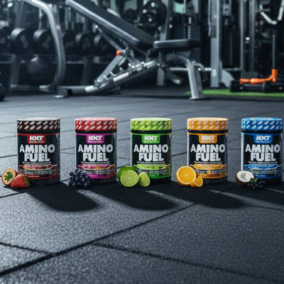 Row of Amino Fuel supplement containers on a gym floor with gym equipment in the background.