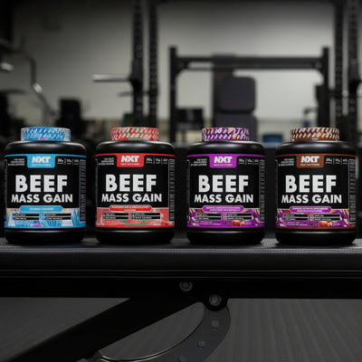 Five bottles of beef mass gain supplement on a gym floor.
