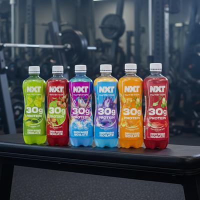 Row of colorful NXT Nutrition protein bottles on a dark surface