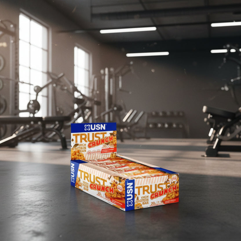 Box of USN Trust Crunch high protein bars on a gym background