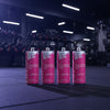 Four pink energy drink cans with silver tops on a gym floor.