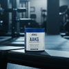 Container of Applied Nutrition AAKG powder on a gym bench with gym equipment in the background