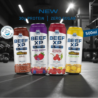 Four cans of Beef XP protein drinks in different flavors on a gym floor.