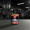 NXT Nutrition Cre Hydrate supplement container with watermelon and strawberry flavour on a gym background.