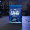 Blue package of Applied Nutrition Creatine Gummies on a gym background