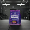 Purple package of Applied Nutrition Creatine Gummies with blackcurrant flavour on a gym background