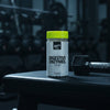 Ghost Essentials digestive enzymes supplement container with a yellow lid on a gym background