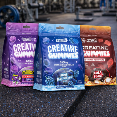 Three packages of Applied Nutrition Creatine Gummies in different flavours on a gym floor.