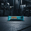 Coco Choco Barebells protein bar on a gym floor with gym equipment in the background