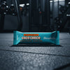 Coco Choco Barebells protein bar on a gym floor with gym equipment in the background