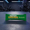 Green protein bar packaging with 'Banana Dream' flavor on a gym floor.