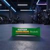 Green protein bar packaging with 'Banana Dream' flavor on a gym floor.