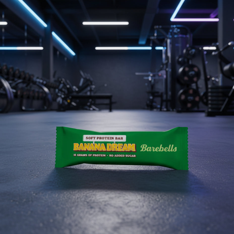 Green protein bar packaging with 'Banana Dream' flavor on a gym floor.