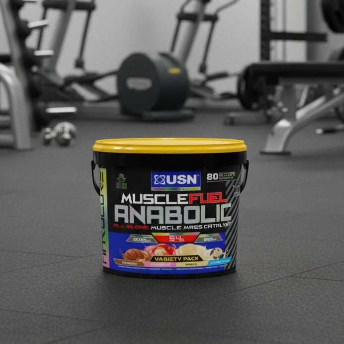 USN Muscle Fuel Anabolic supplement container on a gym floor with exercise equipment in the background