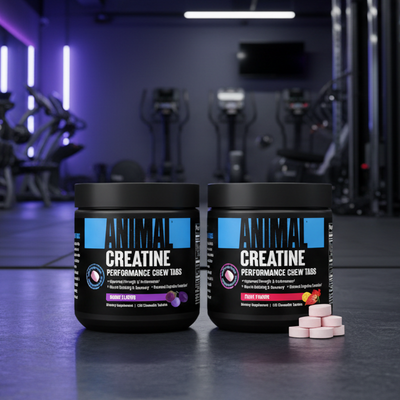 Two containers of 'Creatine Performance' supplement on a gym floor with equipment in the background.