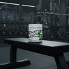 Ghost BCAA supplement container with colourful label on a gym background