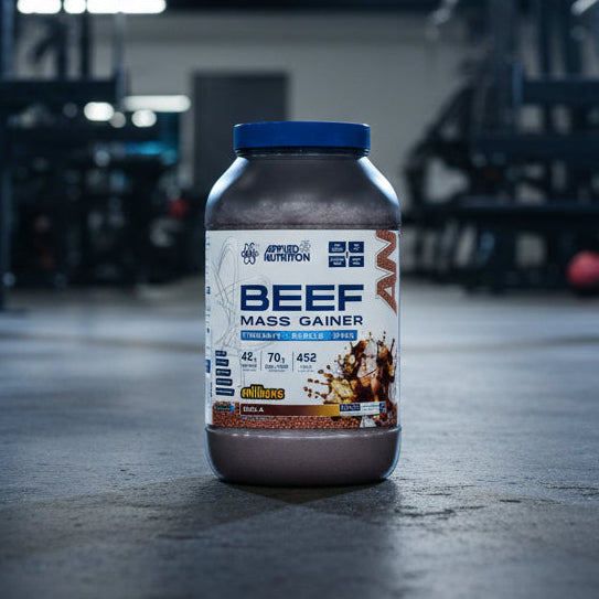 Beef mass gainer supplement container with Applied Nutrition branding on a gym background