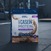 Package of Applied Nutrition 100% Casein Protein Powder in Chocolate Cream flavour on a gym background.