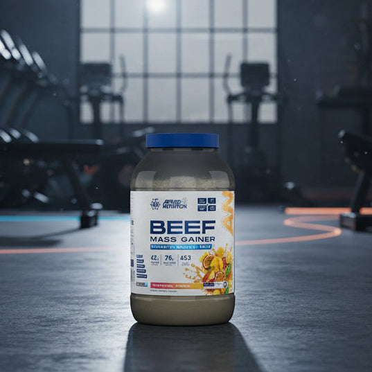 Beef mass gainer supplement container with Applied Nutrition branding on a gym background